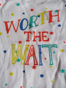 A baby vest featuring the words "worth the wait"